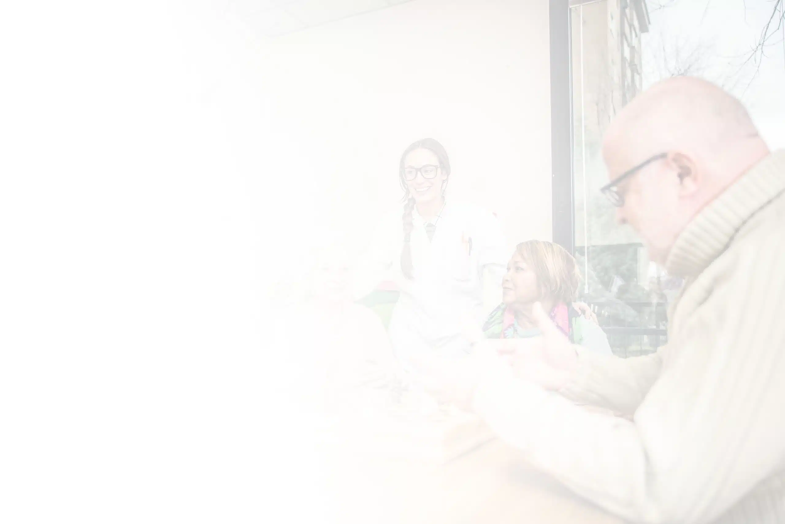 A blurred image features an elderly man and woman sitting at a table, possibly playing a game, in North Pines Assisted Living. A female medical professional is standing beside them, smiling. Another person is partially visible at the edge of the image. They appear to be in a well-lit room.