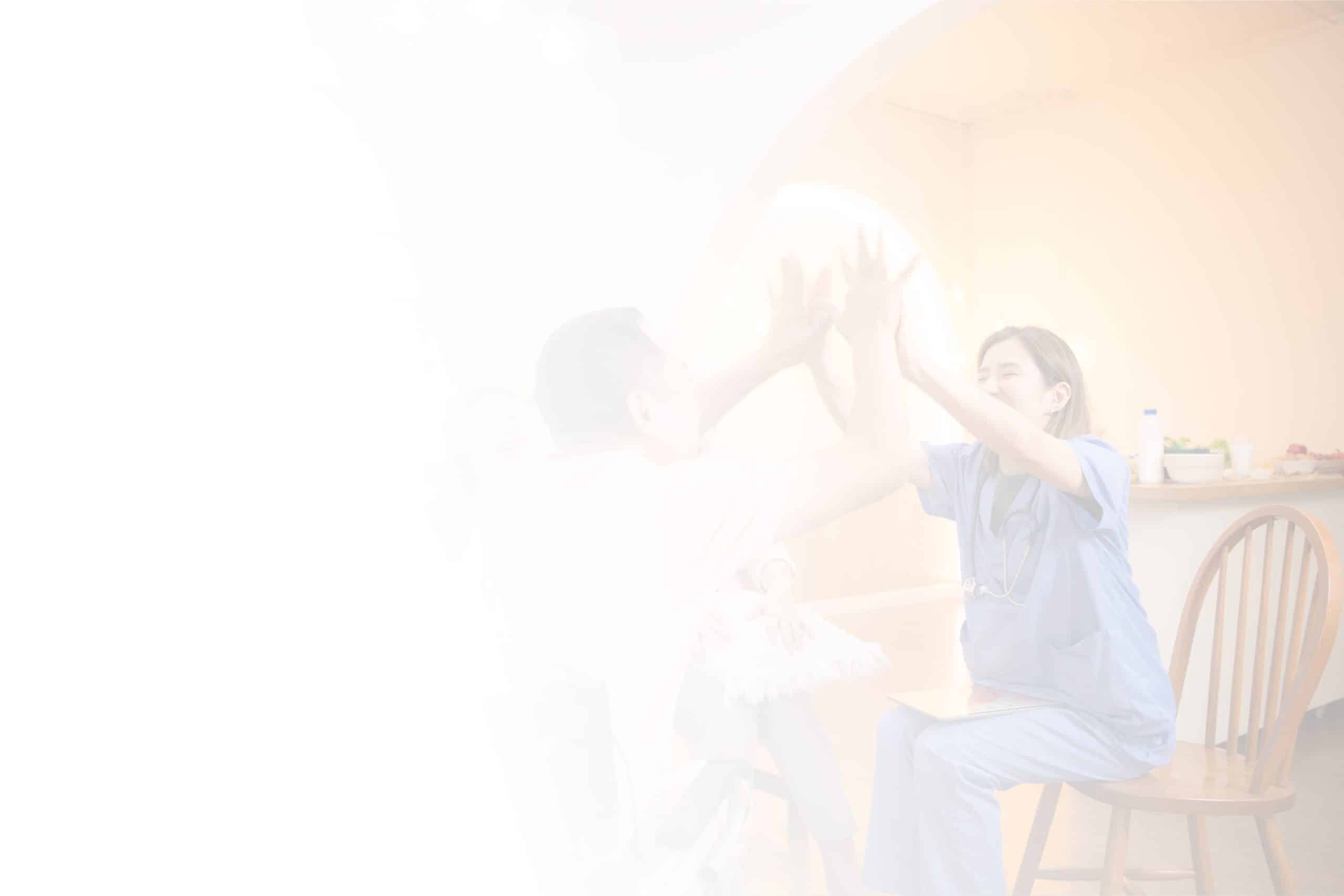 A healthcare worker in blue scrubs is joyfully high-fiving an individual seated in front of them. The background is heavily washed out by bright light, creating a soft, hazy atmosphere. The scene appears to take place in North Pines Assisted Living, fostering a warm and caring environment.